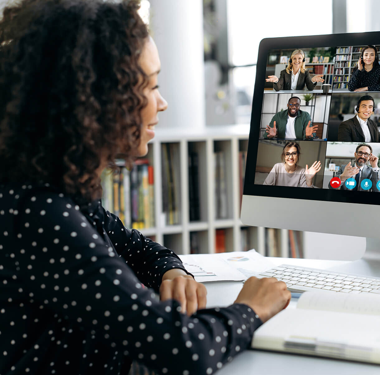 A woman sitting in front of a computer with a group of people on the screen.