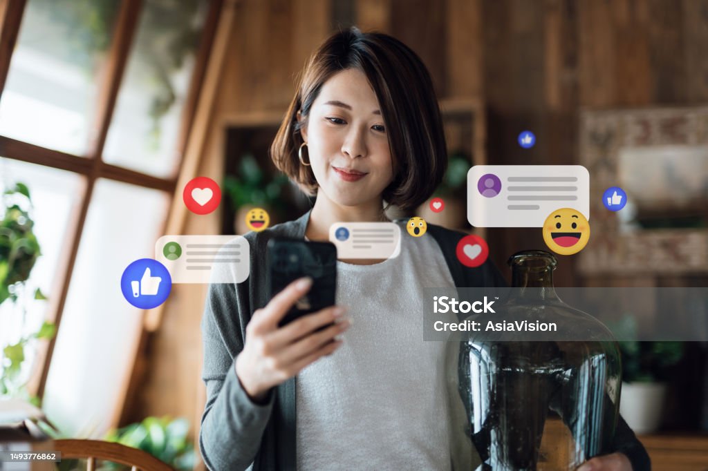 Asian woman using a smart phone with emoticons stock photo.