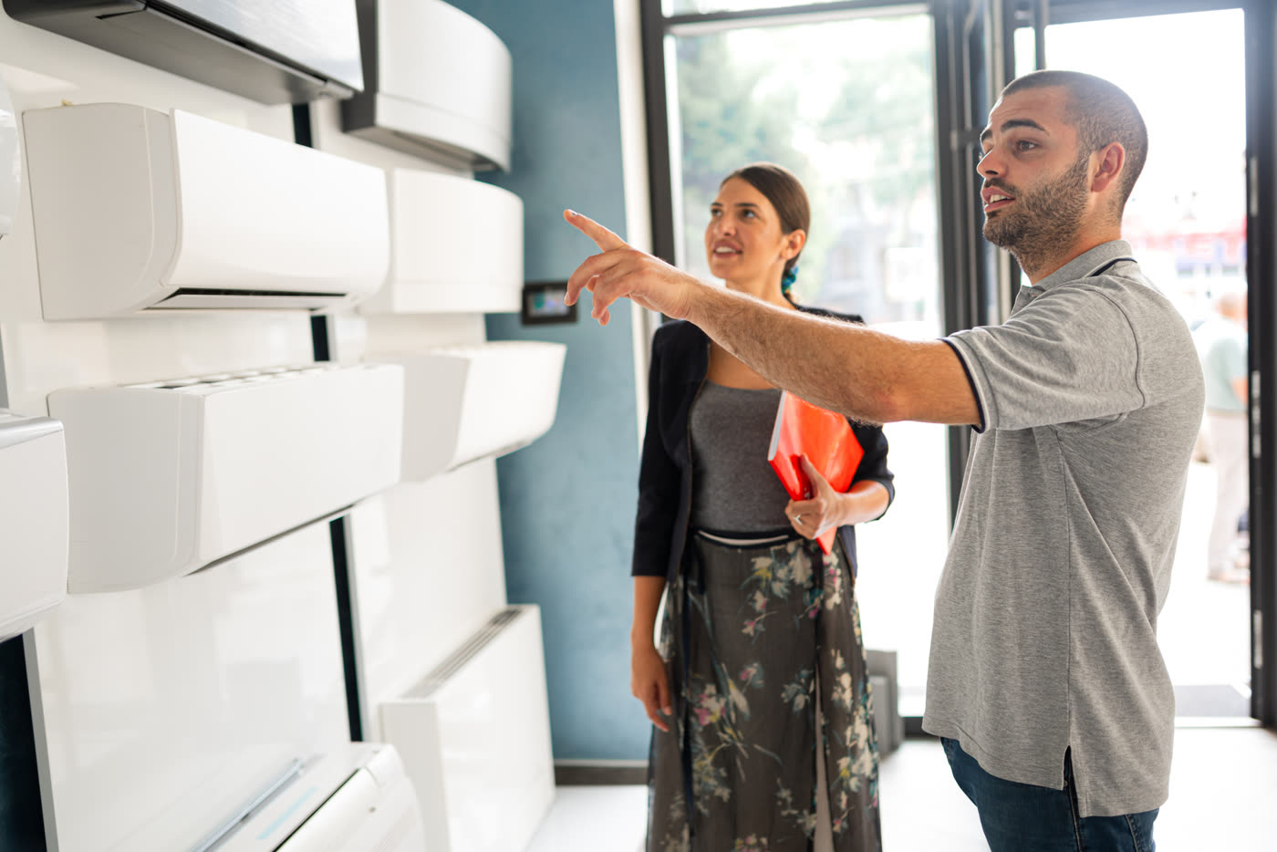 Two people reviewing wall-mounted air conditioning units